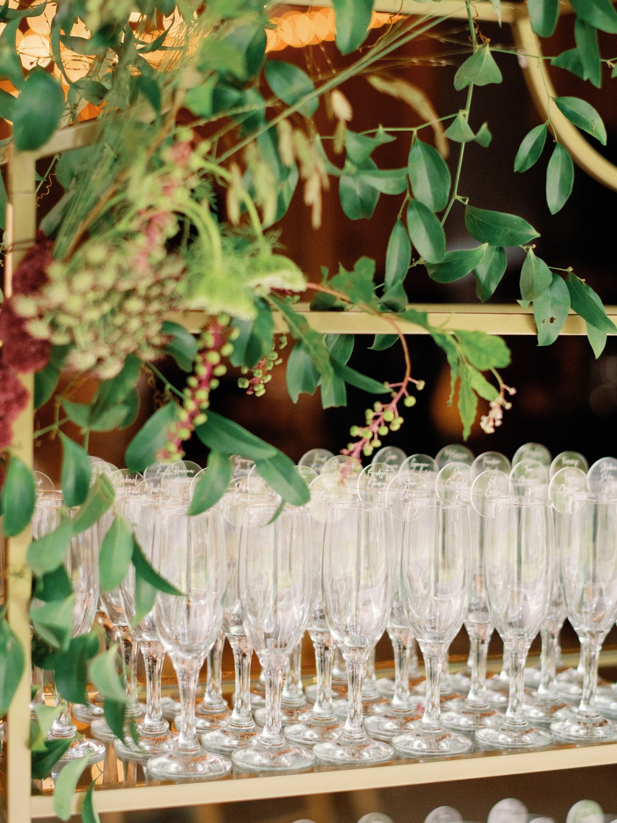 Champagne flutes with personalized tags, adorned with greenery