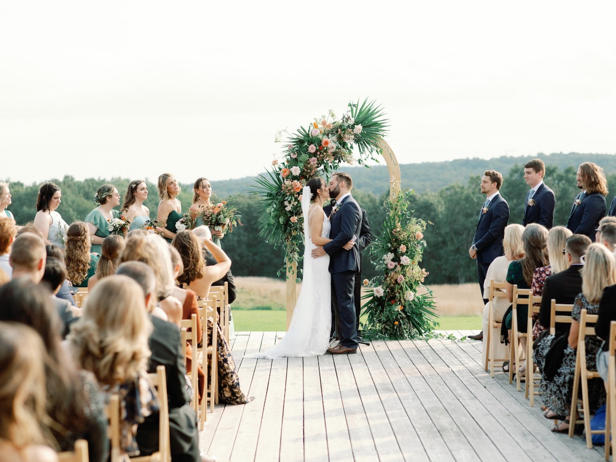Bride and groom kissing at outdoor wedding ceremony