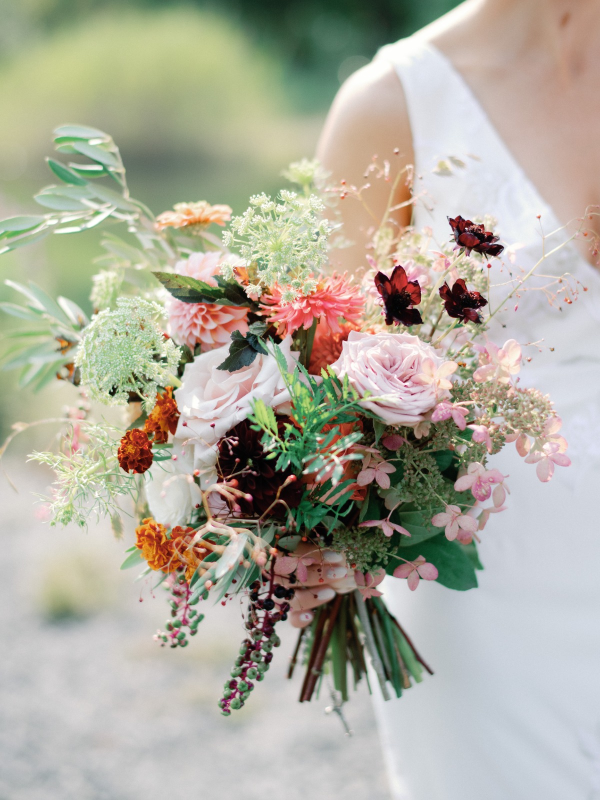 Bride holds a stunning wedding bouquet of roses dahlias