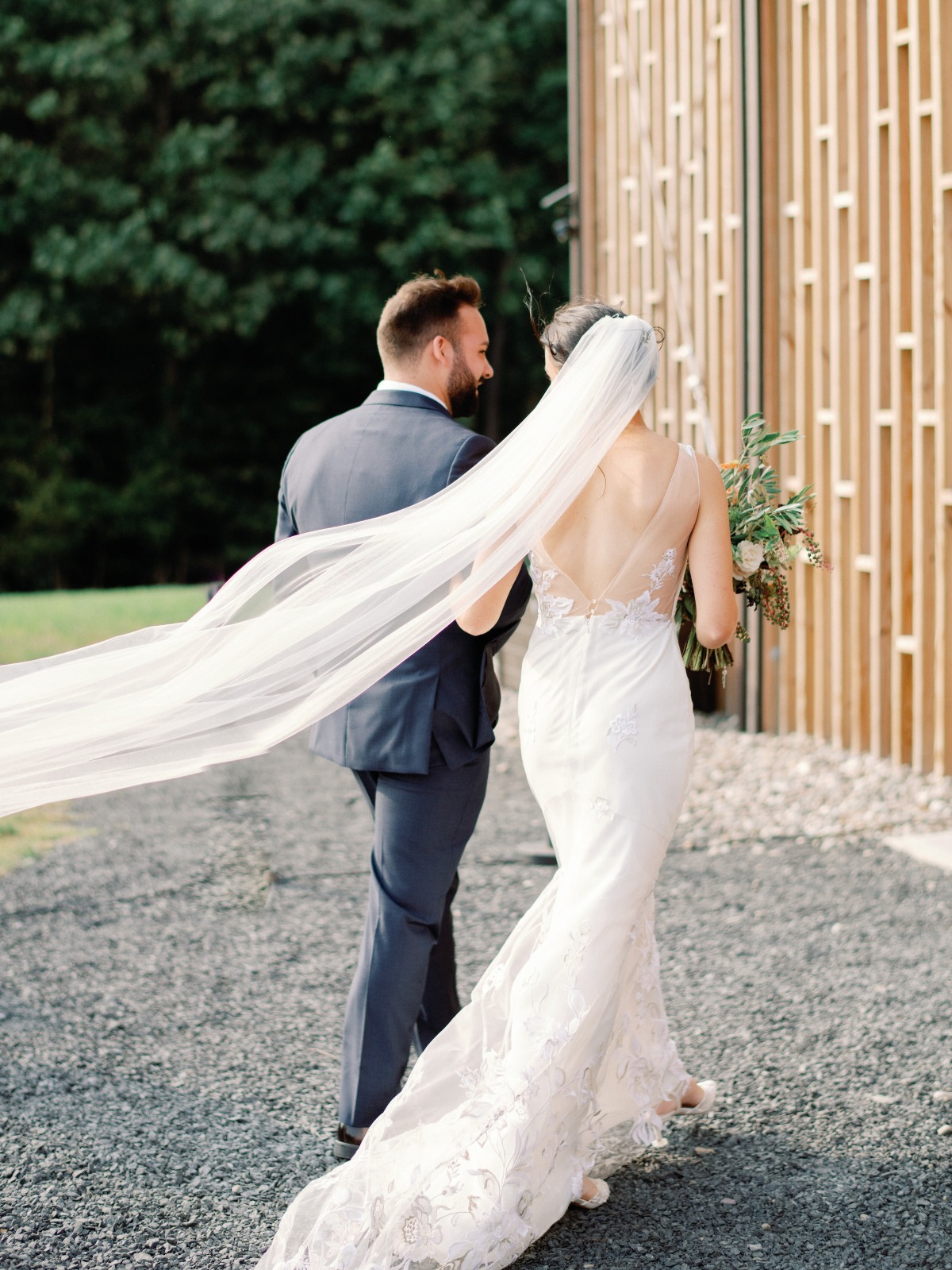 Bride and groom walking away, wedding veil flowing