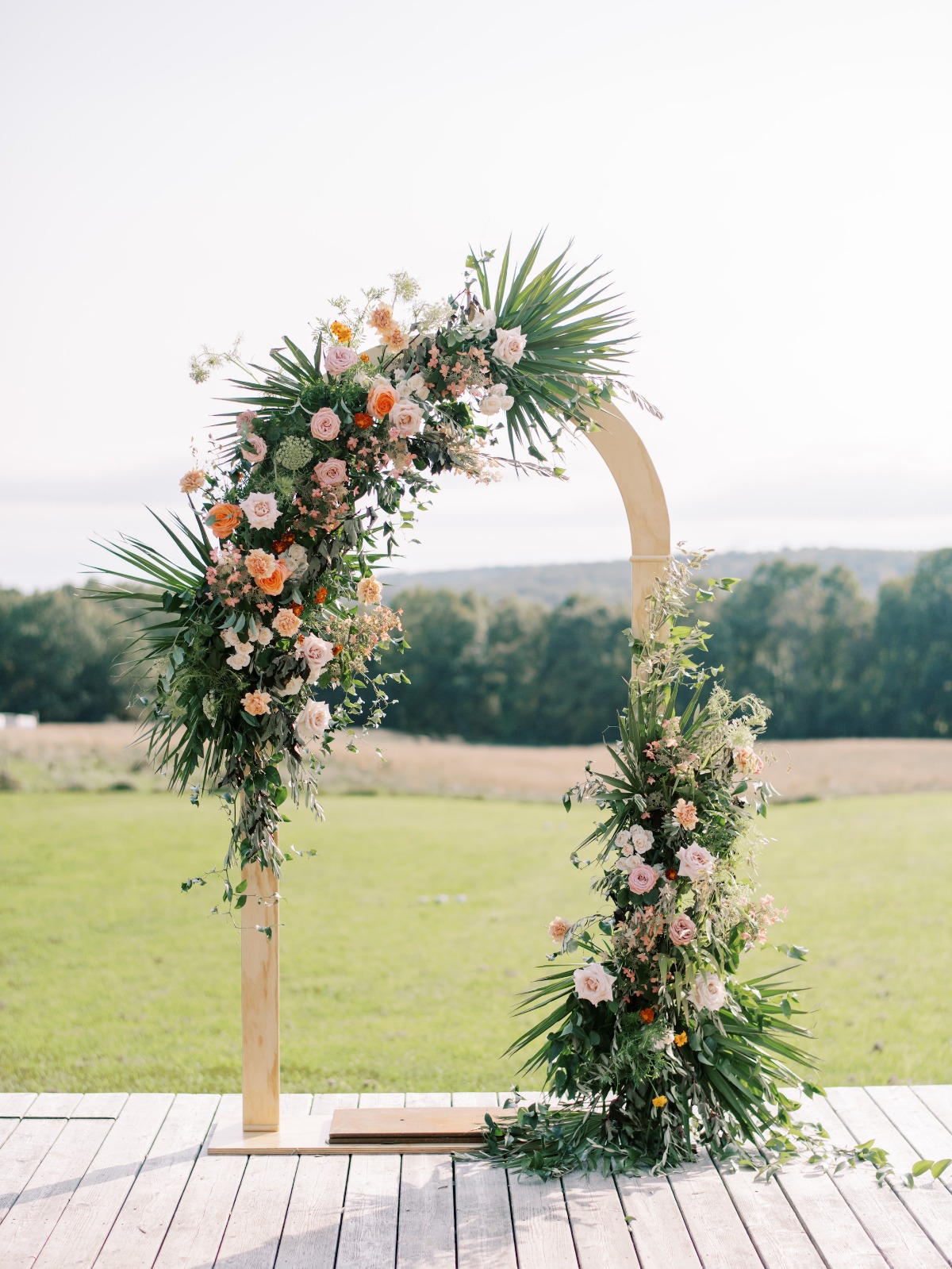 Floral wedding arch outdoors: peach and pink blooms