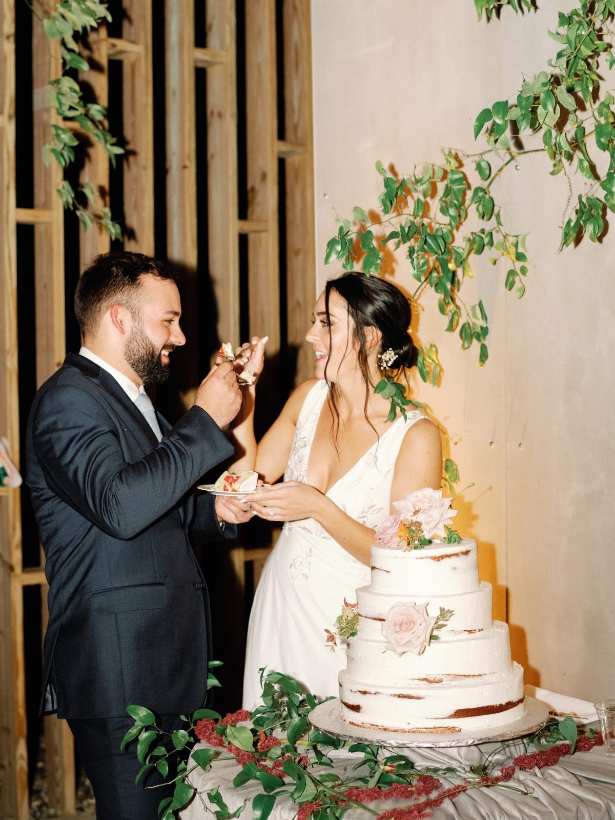 Newlyweds feeding each other wedding cake at reception