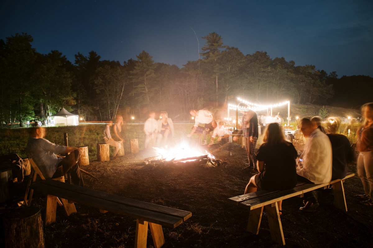 People gathered around a bonfire at night, camping event