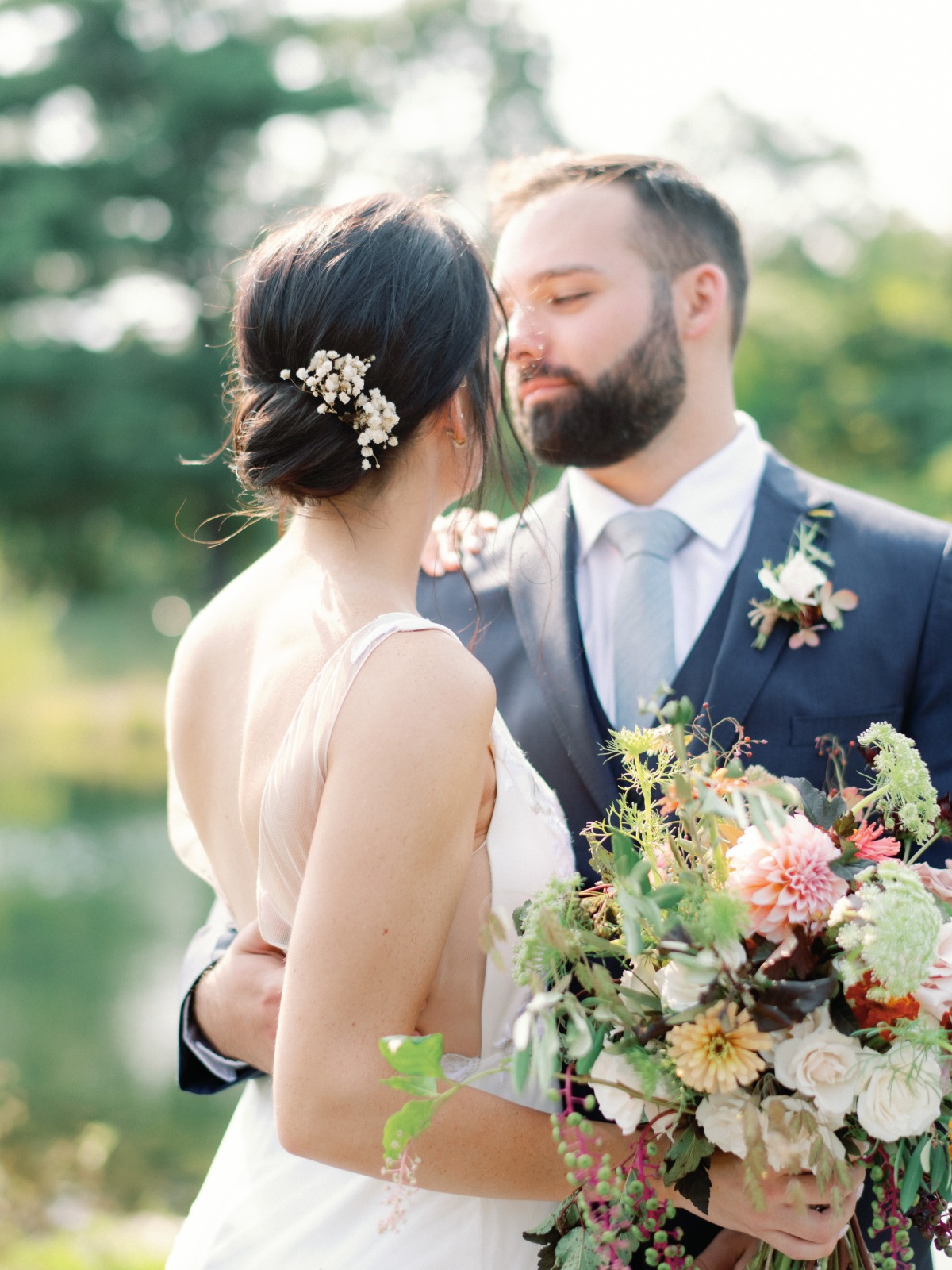 Bride and groom embrace in outdoor wedding portrait