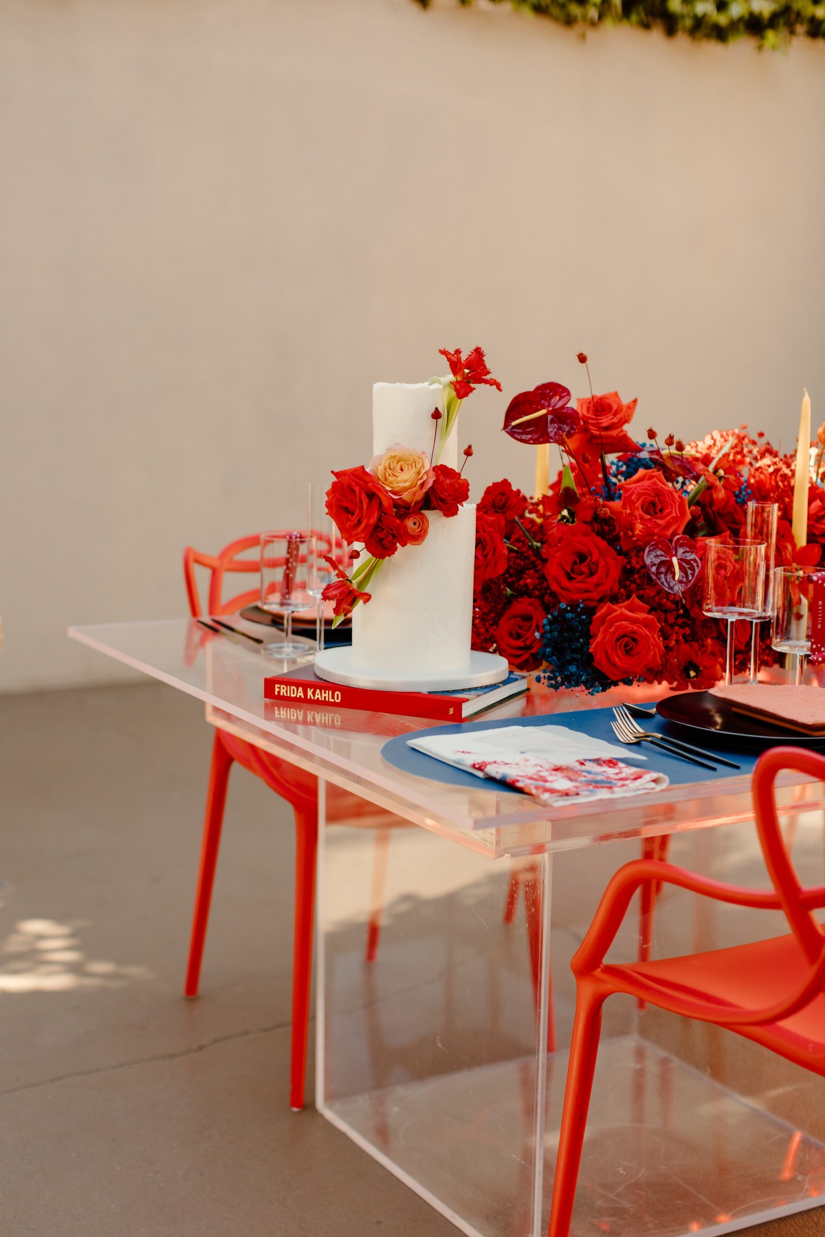 Elegant wedding cake with red floral arrangement on table