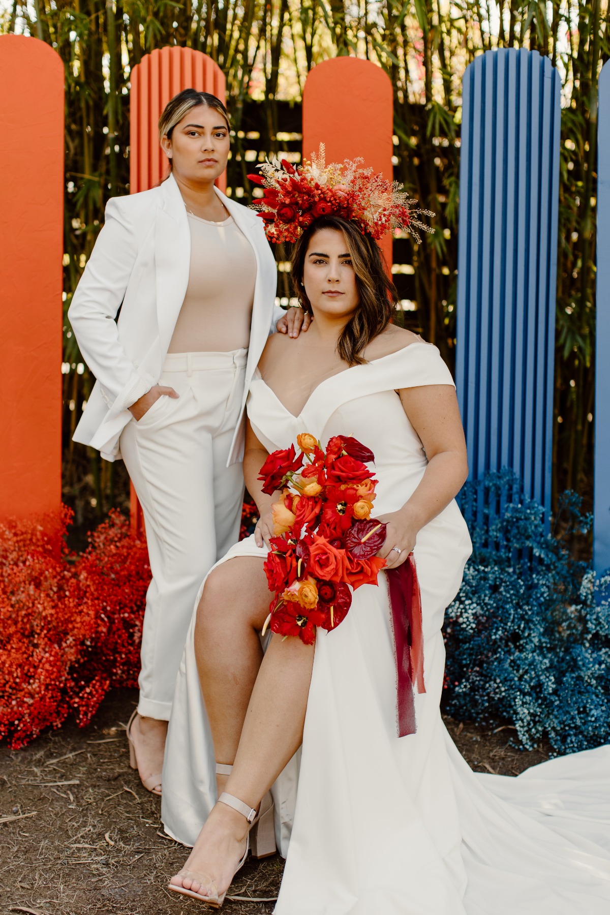 Two brides in elegant white wedding attire pose outdoors