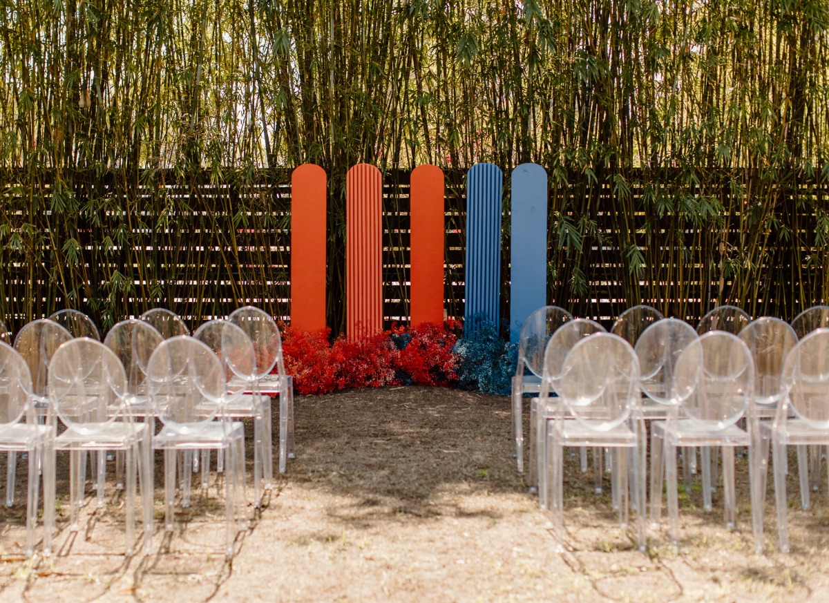Outdoor wedding ceremony with acrylic chairs and bright backdrop