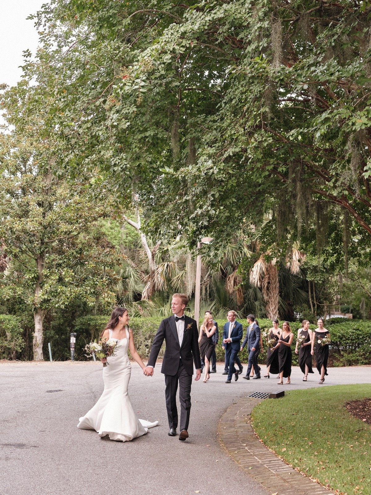Bride and groom holding hands followed by wedding party