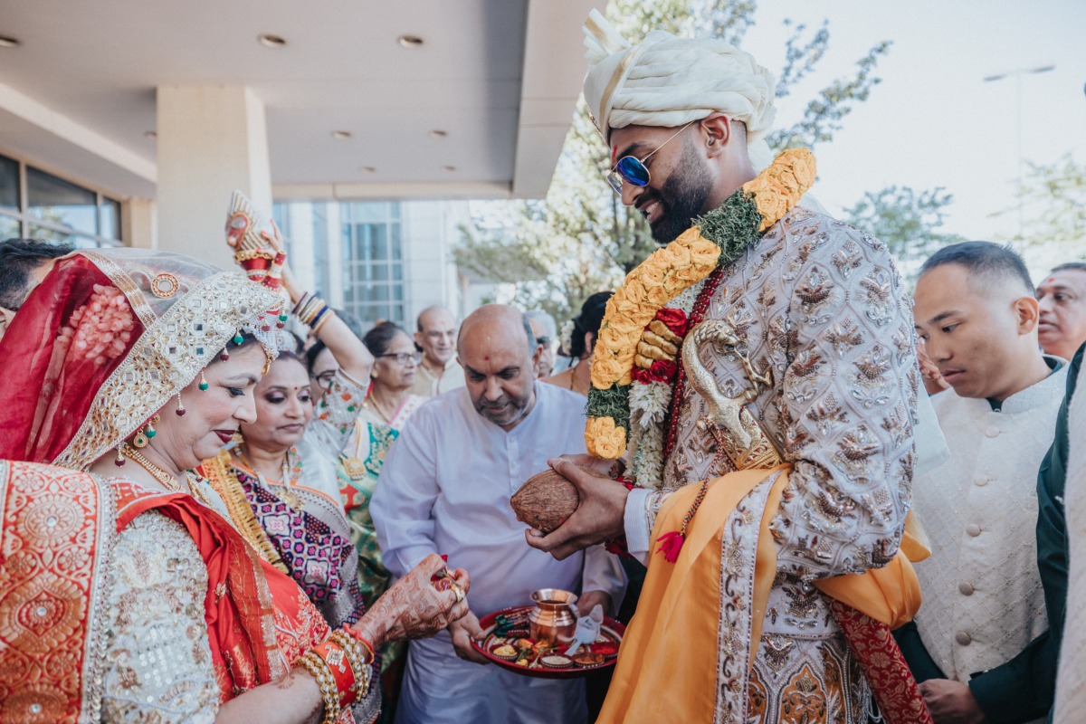 Groom wearing garlands and greeting family leading in to wedding ceremony
