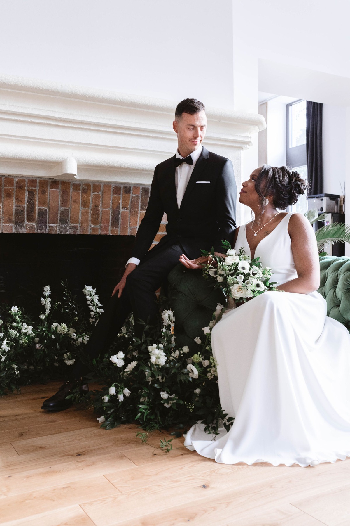 Portrait of bride and groom in front of florals and fireplace