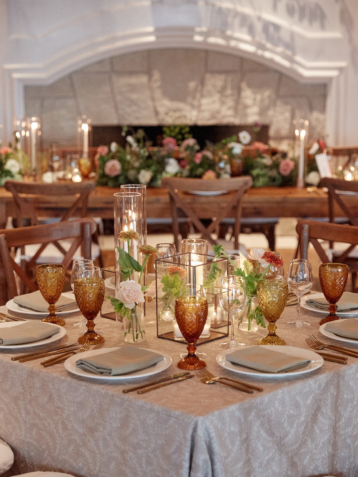 Reception tables with place-settings, glasses, and centerpieces with candles