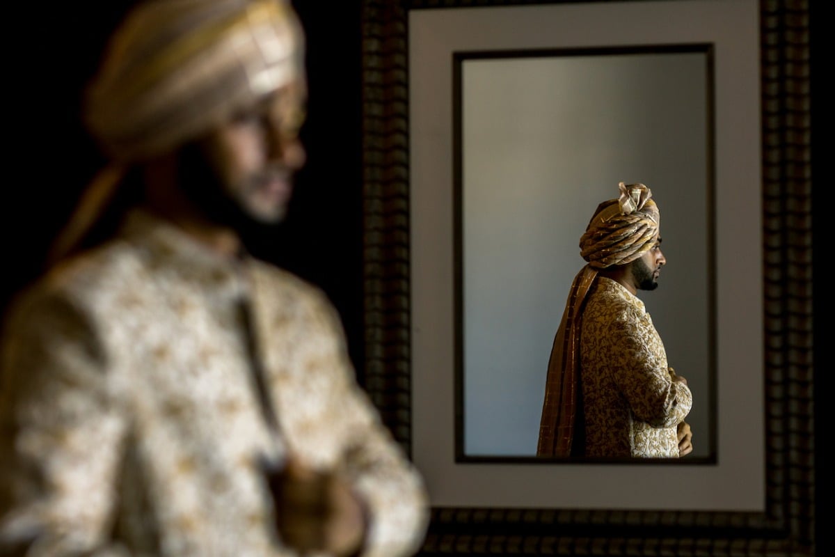 Groom in traditional Hindu wedding attire in mirror