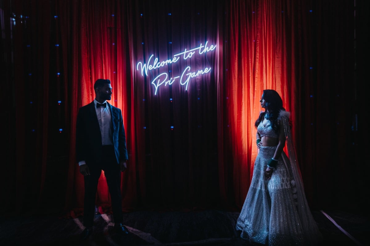 Bride and groom next to customized neon sign at reception
