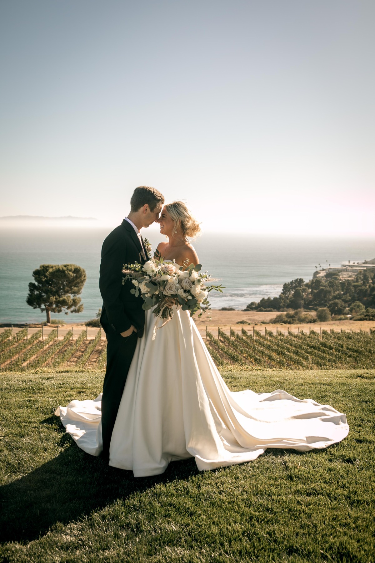 Portrait of bride and groom in front of vineyard next to ocean