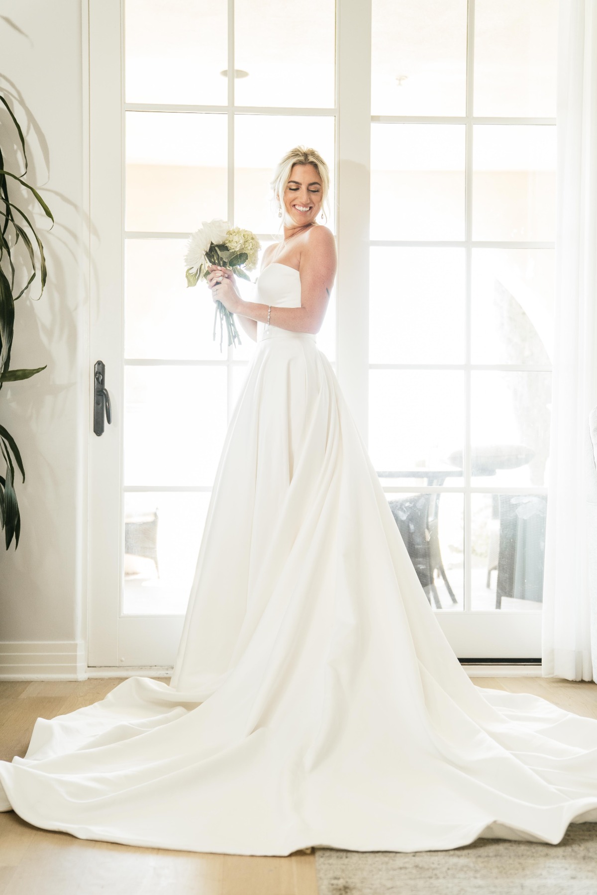 Bridal portrait holding bouquet in front of window