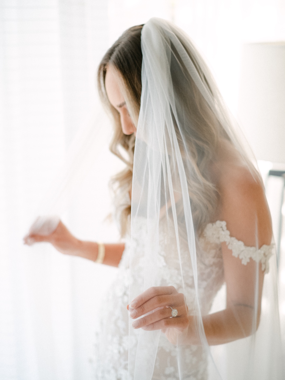 Bride looking down behind tulle veil 