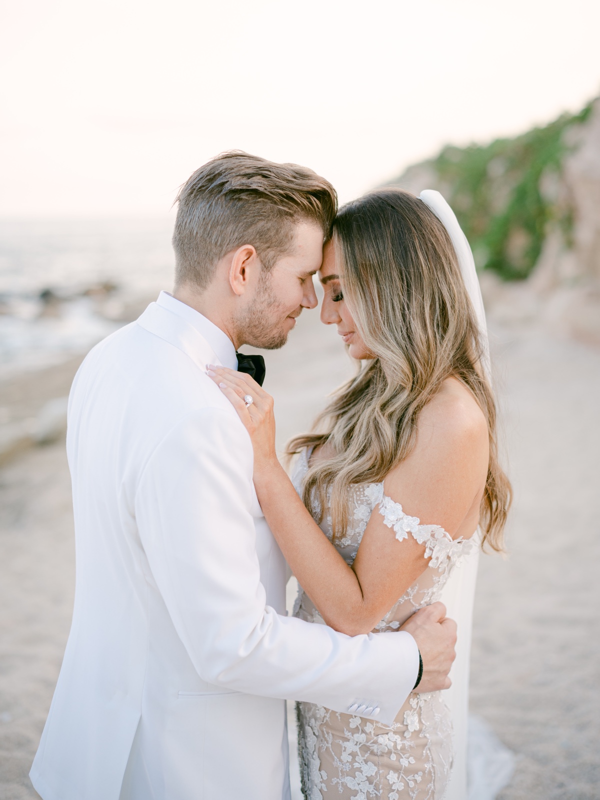 Bride and groom with foreheads touching on beach