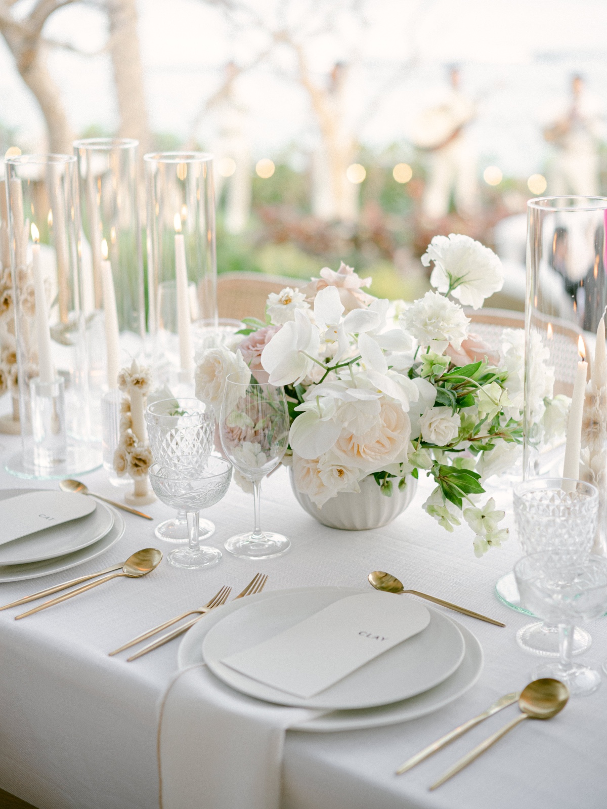 Close up of place setting with crystal glasses and white and pink floral centerpiece