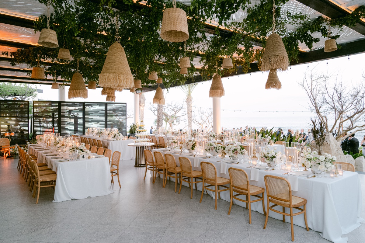 Overall view of reception area with hanging lights, long rectangular tables and floral arrangements
