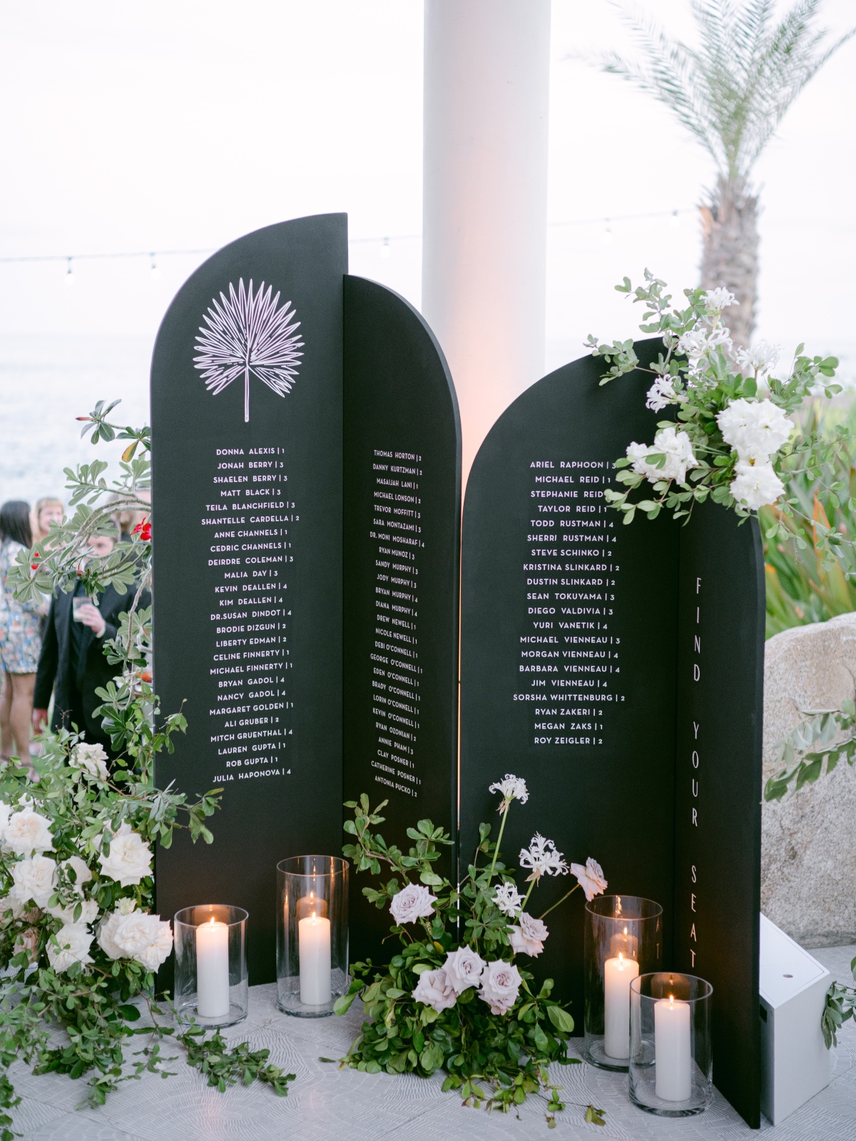 Black seating arrangement signs with candles and anemone flowers around
