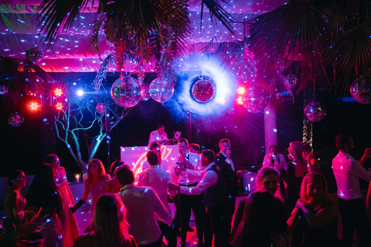 Guests dancing under disco balls at reception with DJ