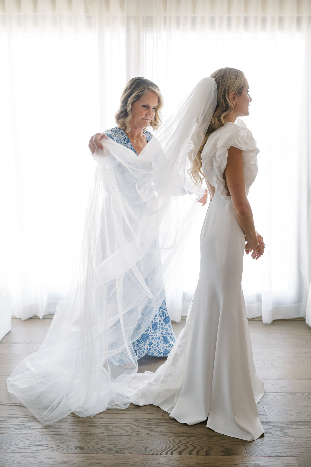 Mother of the bride helping bride with veil