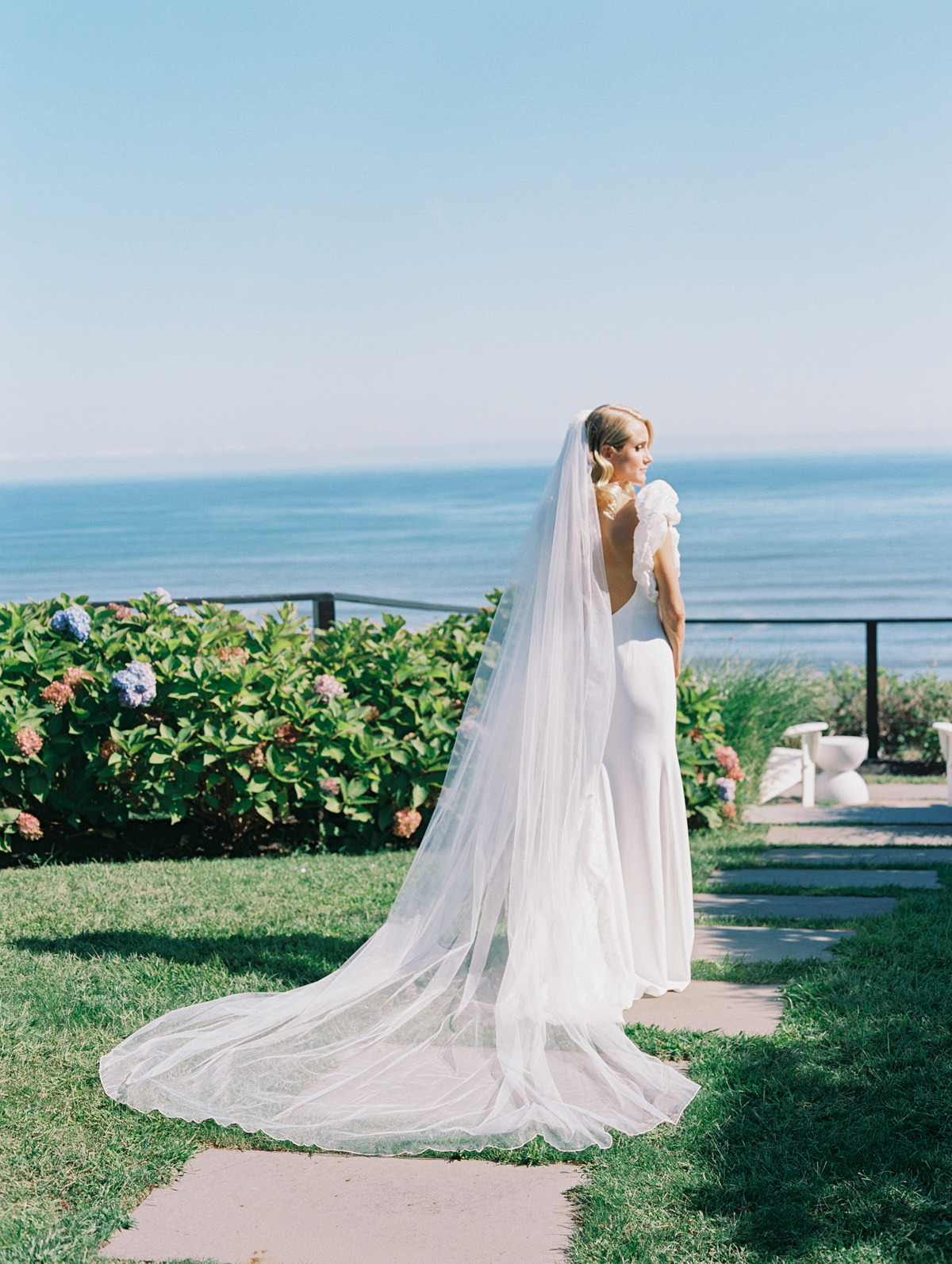 Portrait of bride's dress and veil in garden by ocean