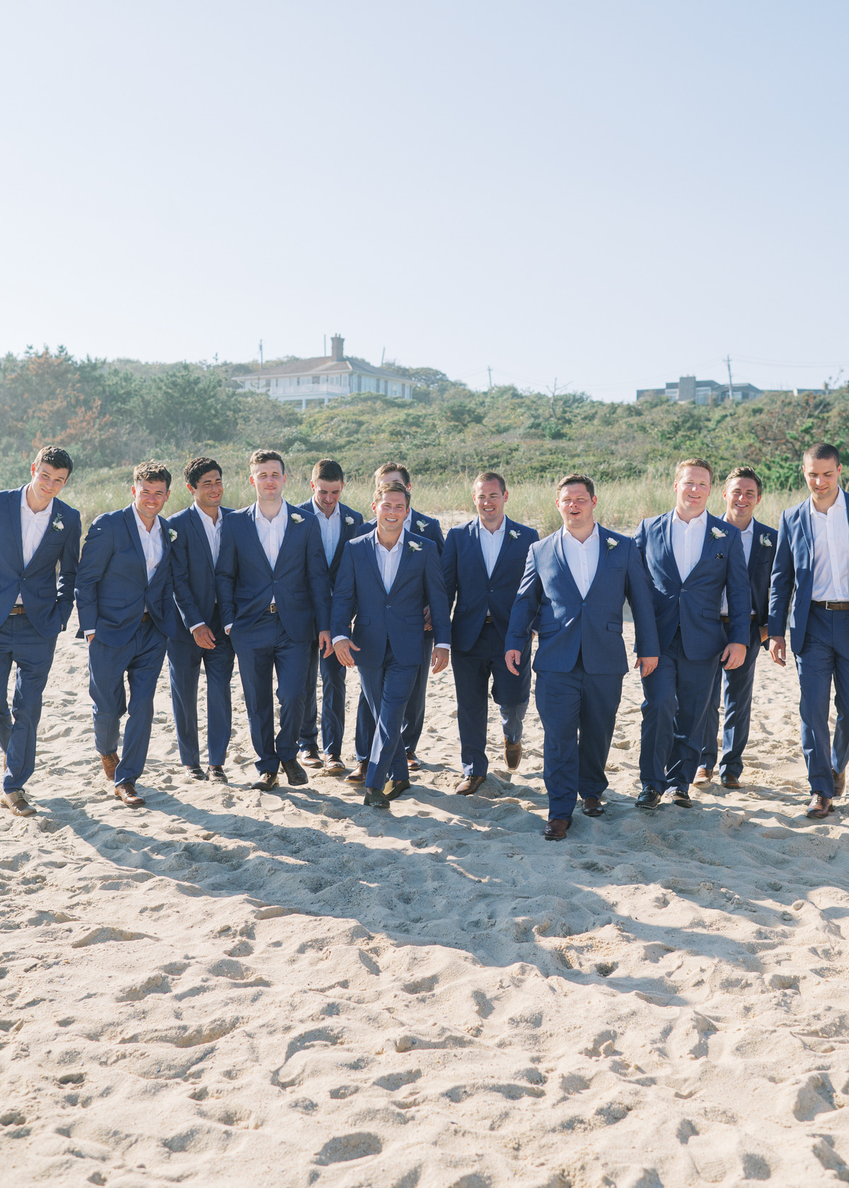 Groom and groomsmen walking in blue suits on beach