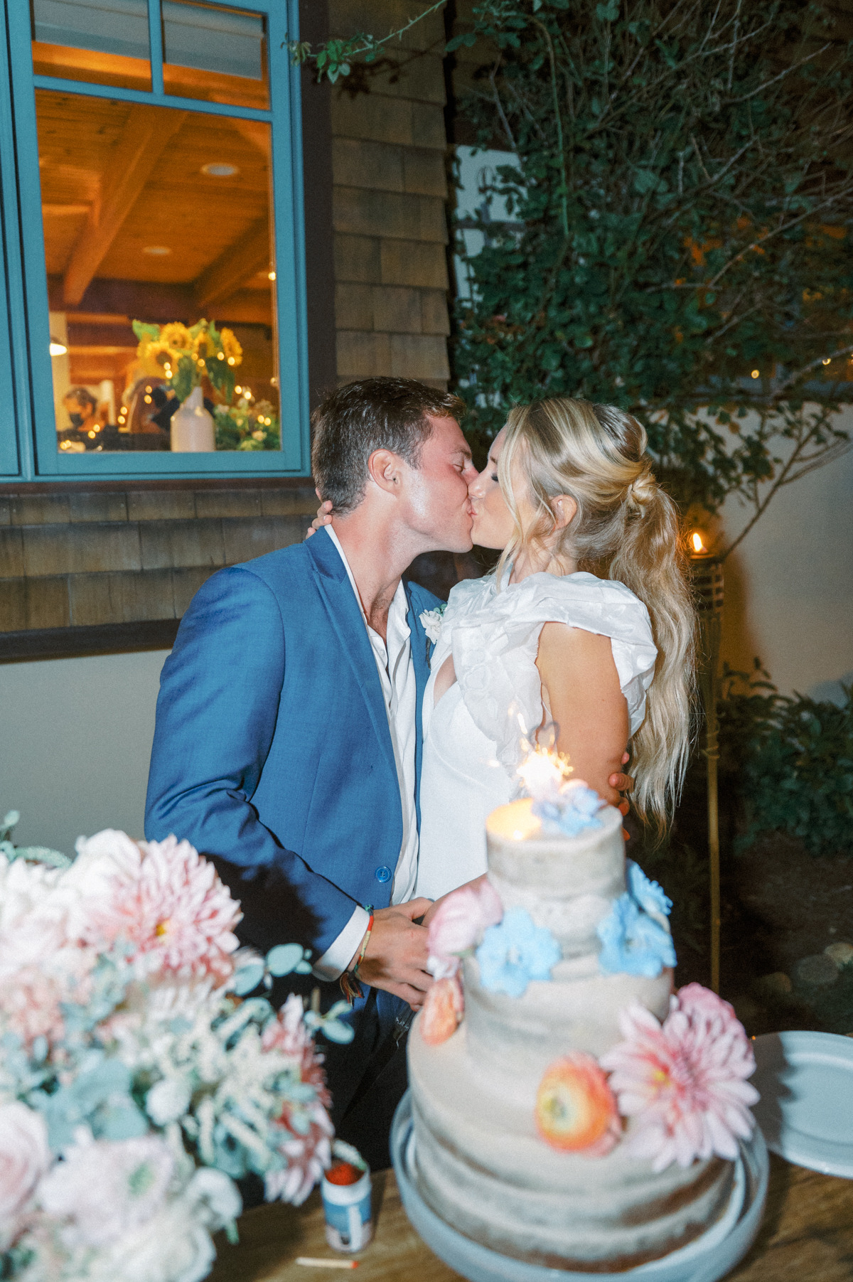 Bride and groom kissing in front of cake table