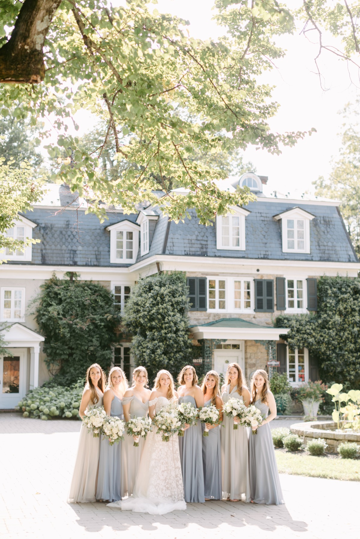 Portrait of bride and bridesmaids holding bouquets in front of inn