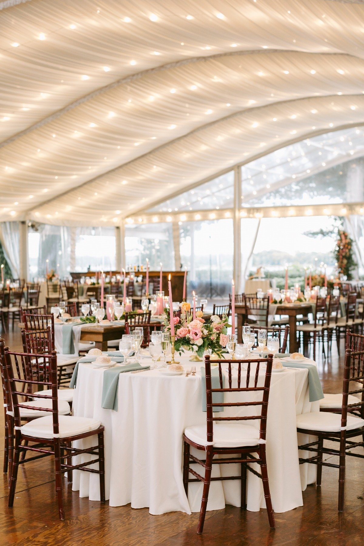 Reception tent with tables, string lights, and centerpieces