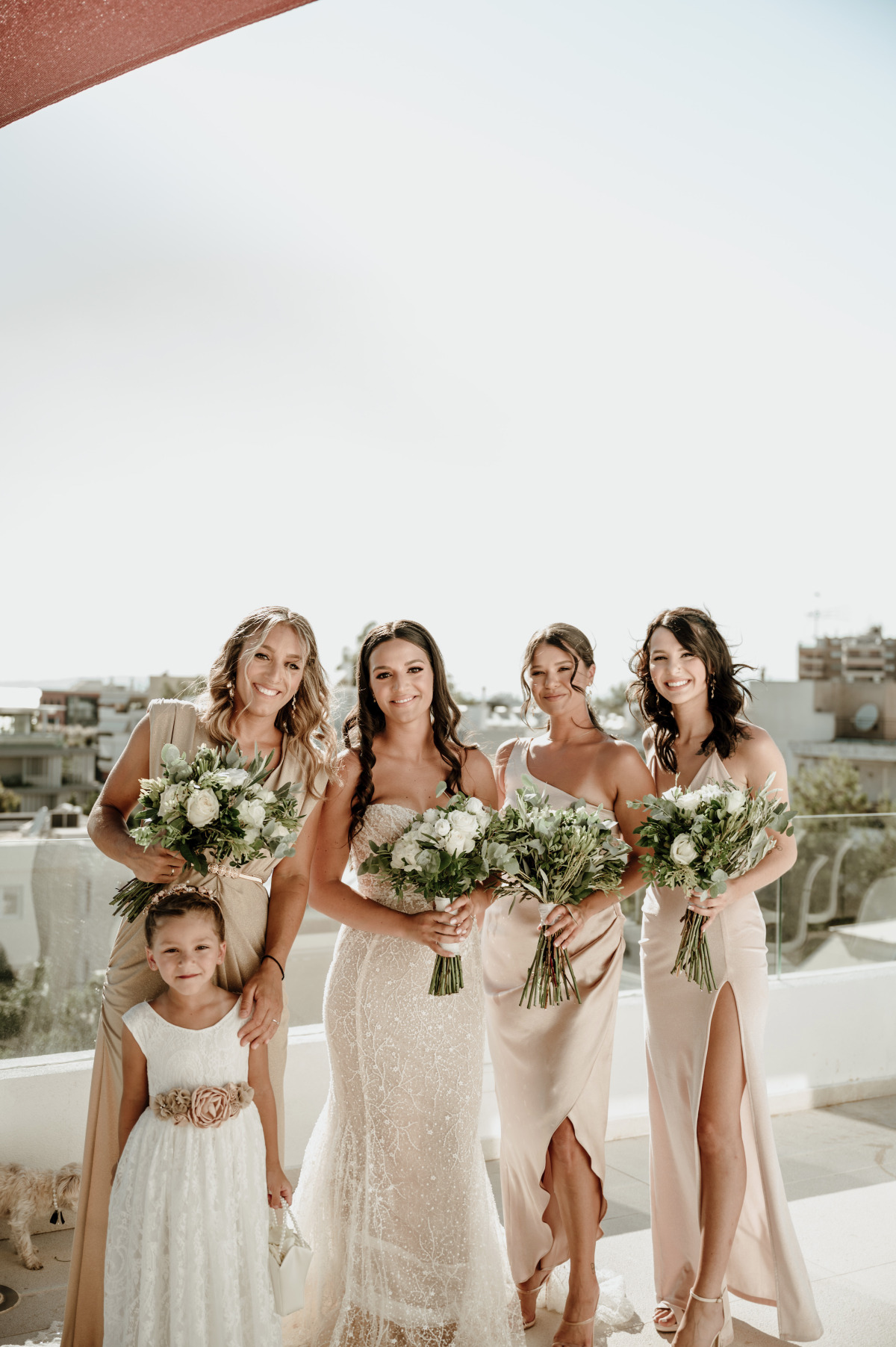 Portrait of bride with bridesmaids in champagne dresses with flower girl 