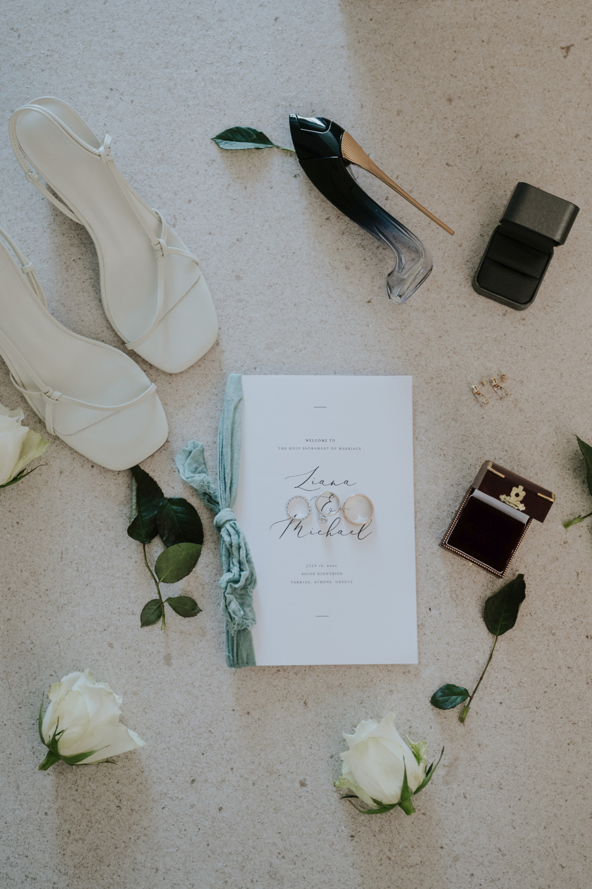 Aerial photo of invitation, rings, shoes, and roses