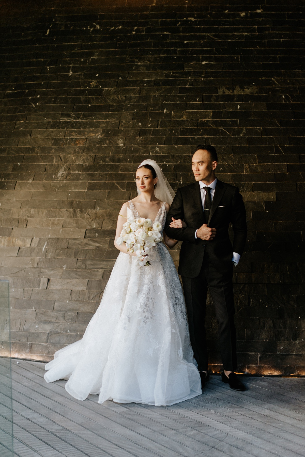 Portrait of bride and groom against brick wall