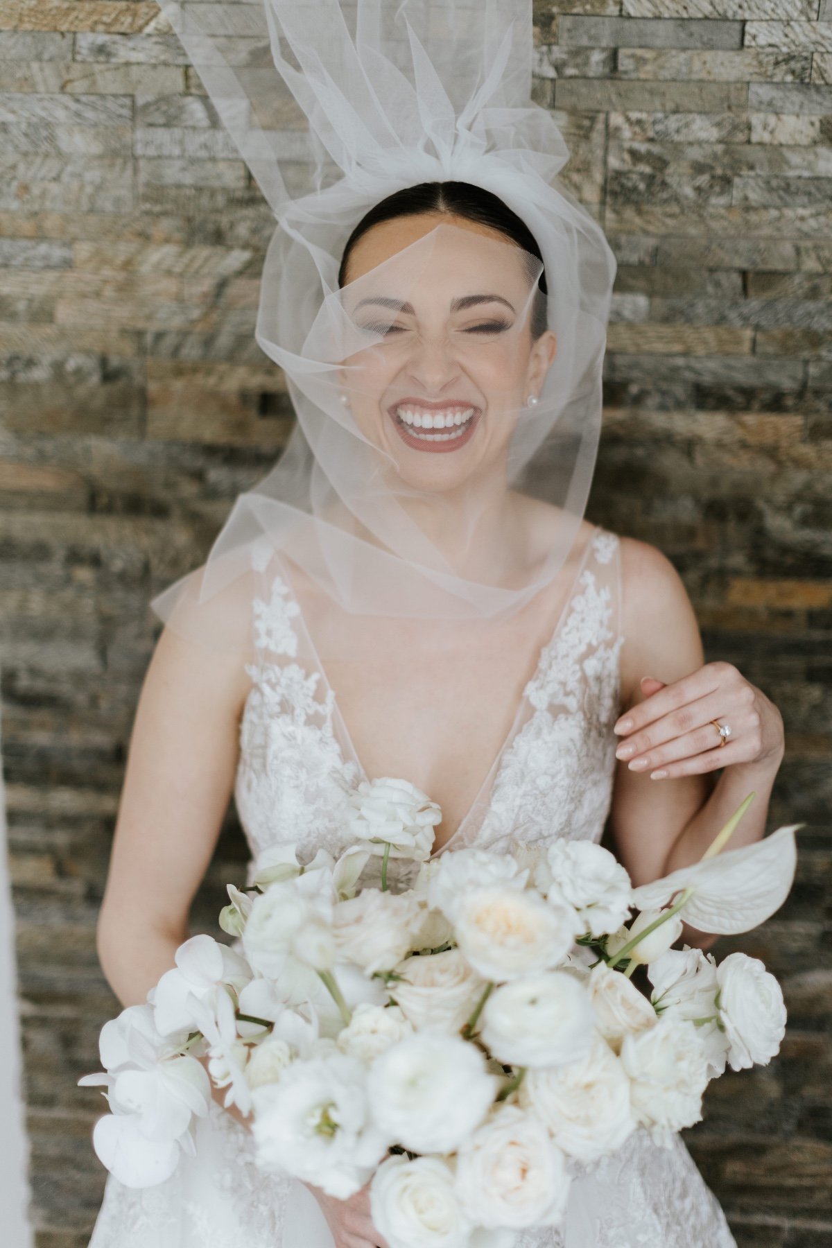 Portrait of bride laughing and wearing veil over her face