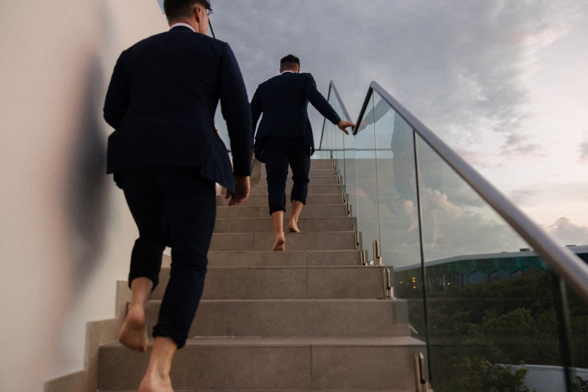 Grooms walking up stairs barefoot at sunset