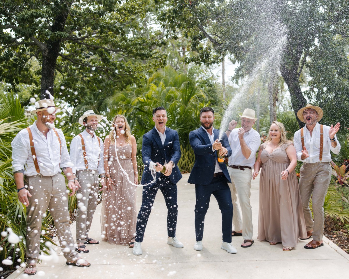 Grooms with wedding party spraying champagne
