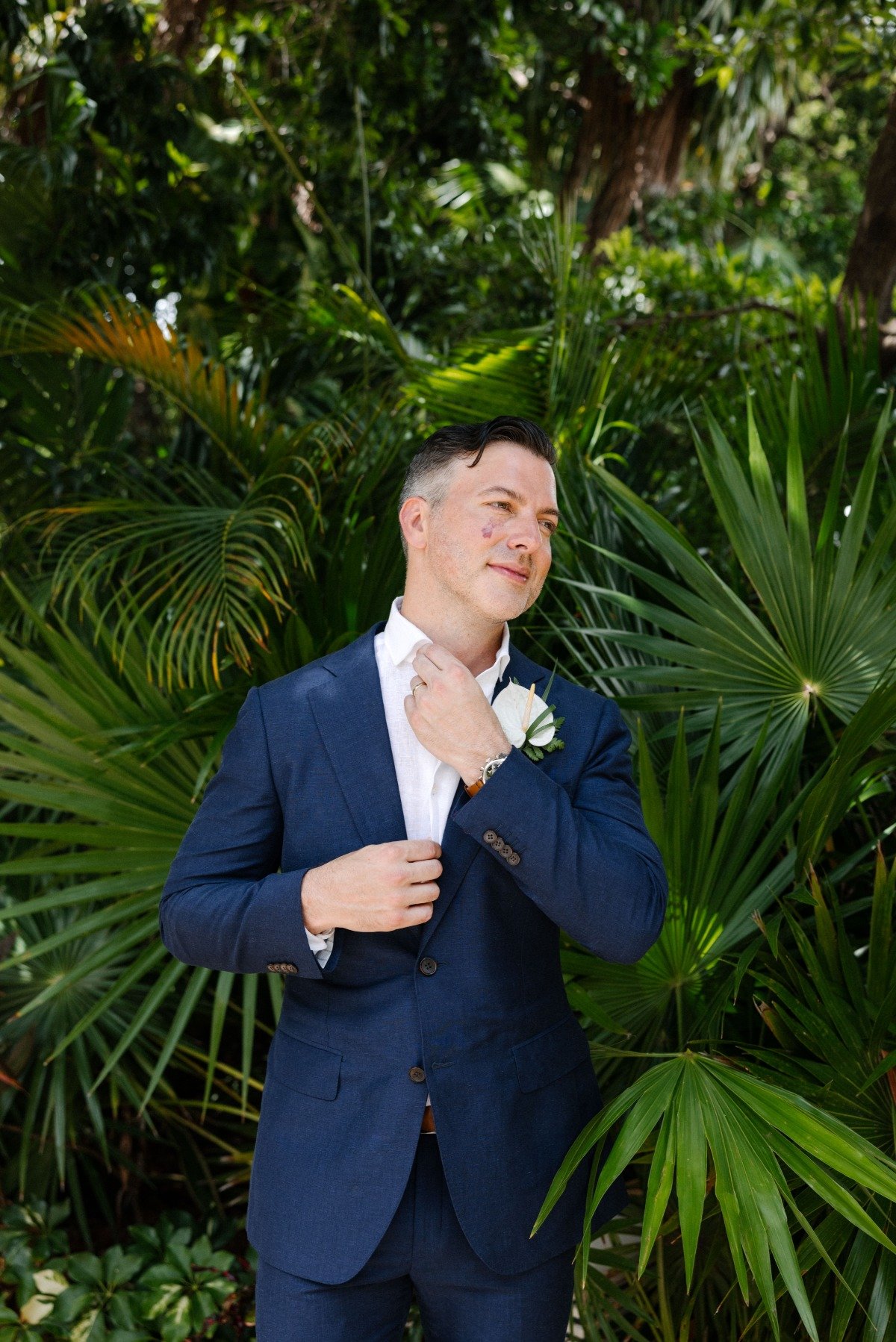 Portrait of groom in front of tropical leaves