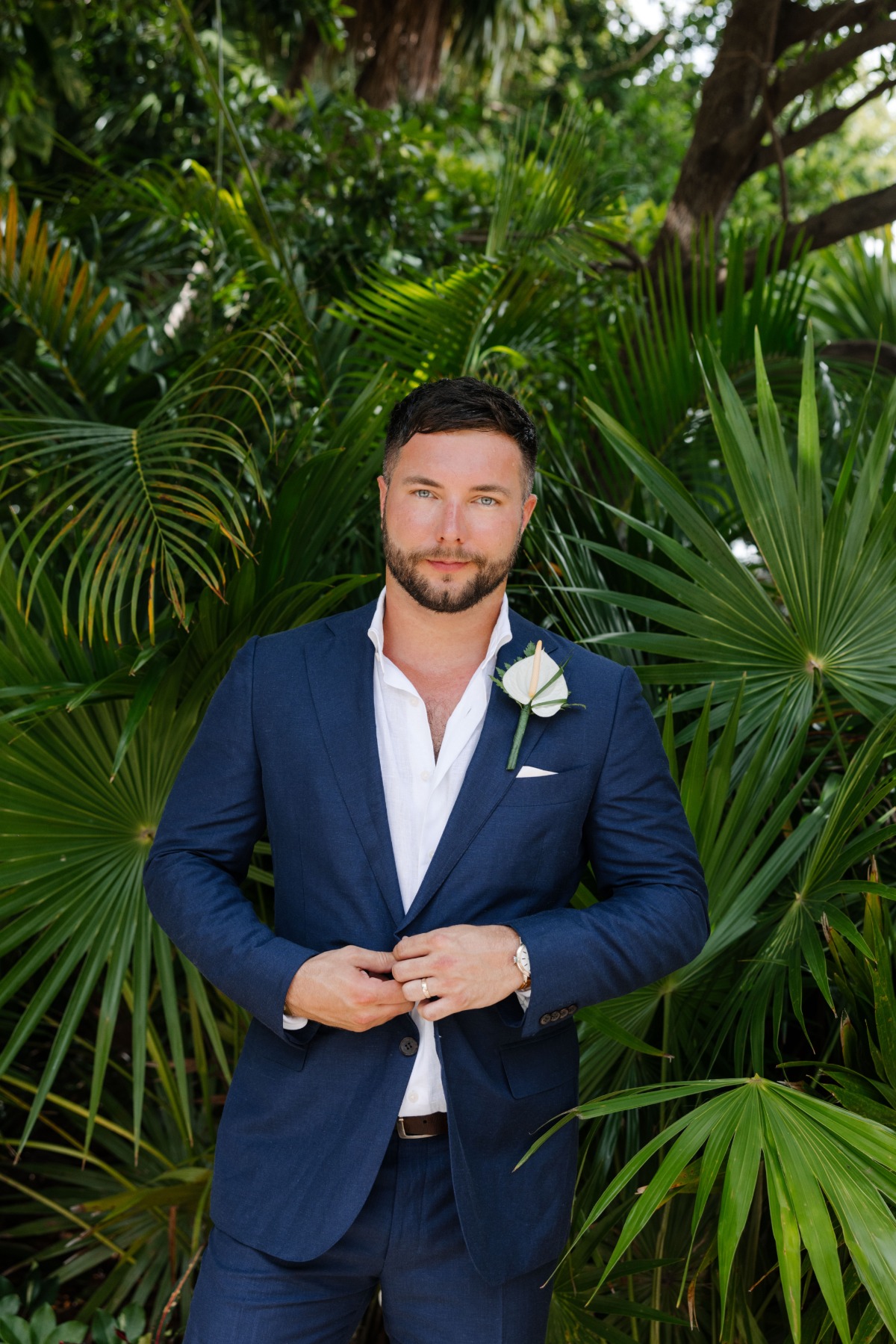 Portrait of groom in front of tropical leaves