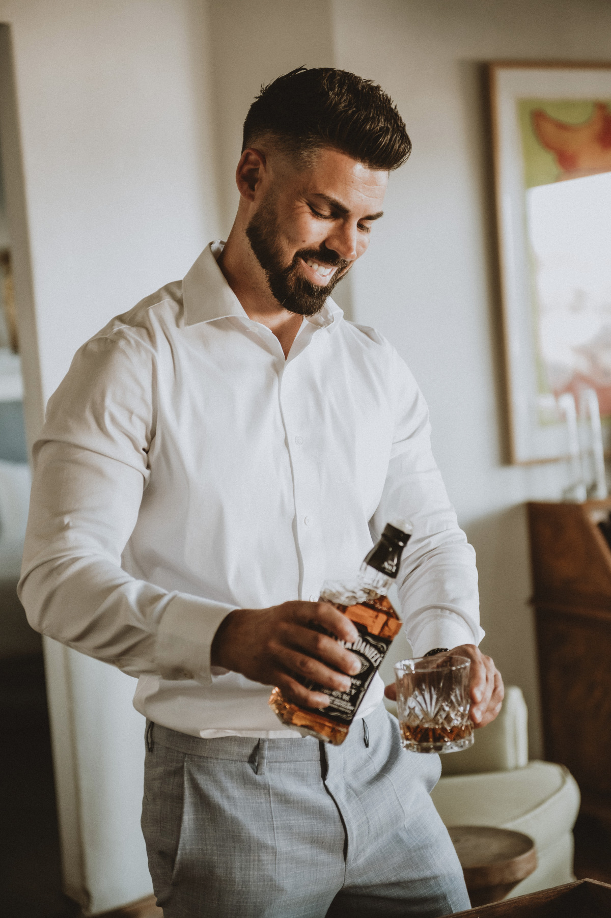 Groom pouring whiskey into glass