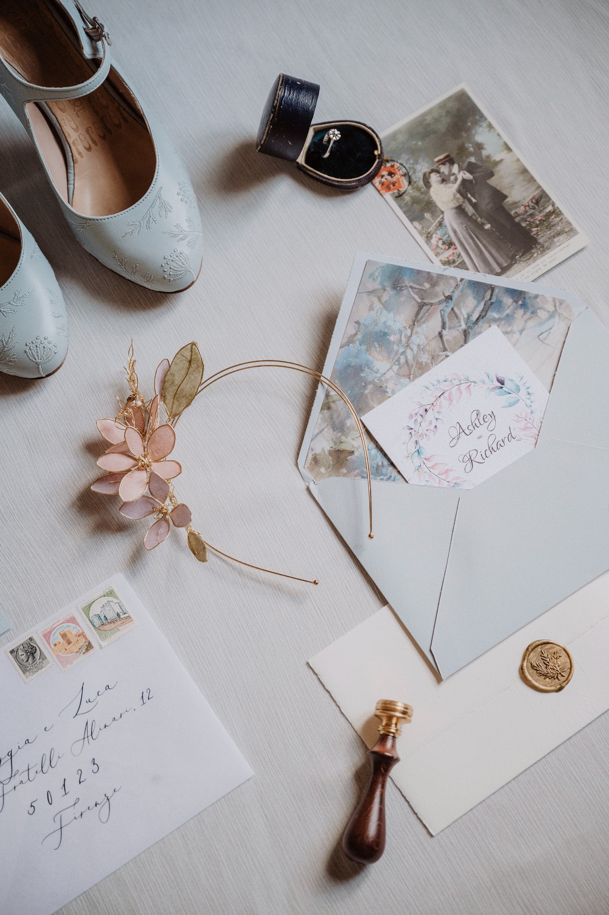 Aerial view of invitation, headpiece, shoes, and wedding bands with vintage photographs
