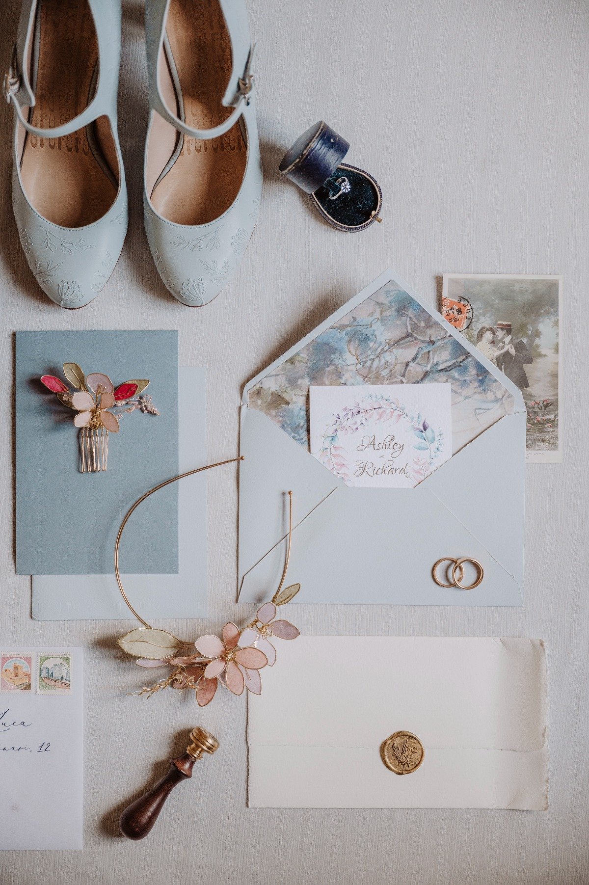 Aerial view of shoes, wedding ring, hairpiece, and invitations