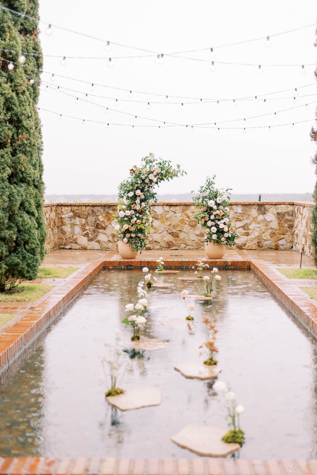 Ceremony space with string lights, floating flowers, and a pond