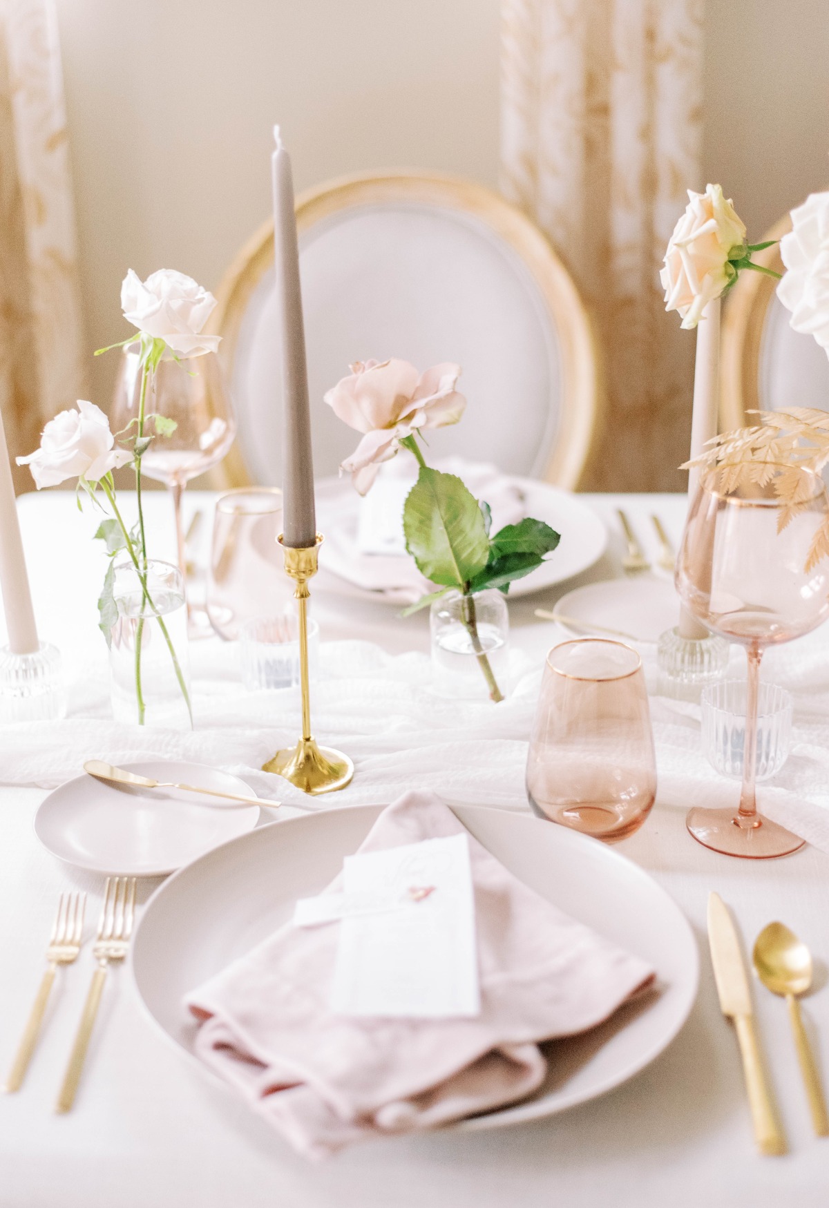 Aerial view of pink place setting with gold utensils and candle holders
