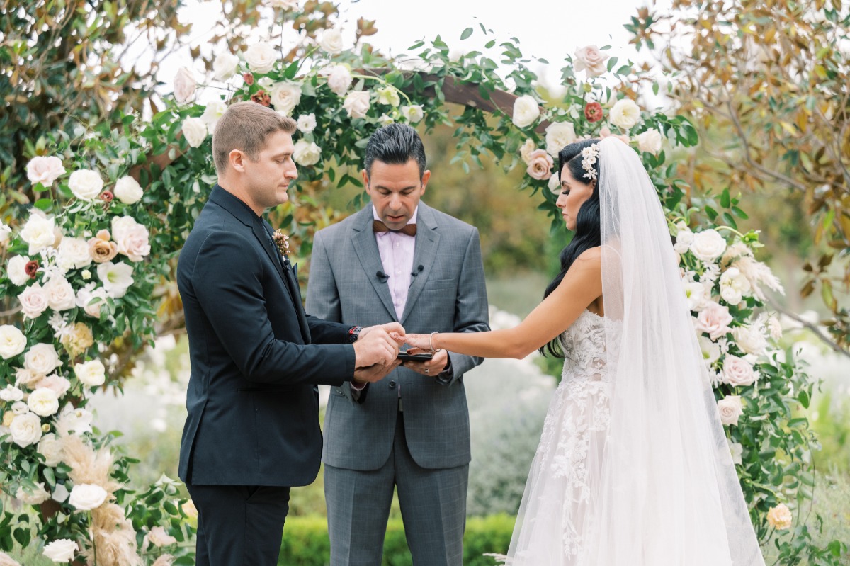 Groom putting ring on bride's finger during ceremony