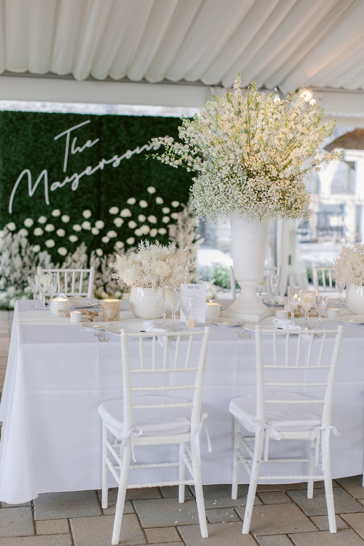 Reception table with centerpieces and grass wall in background