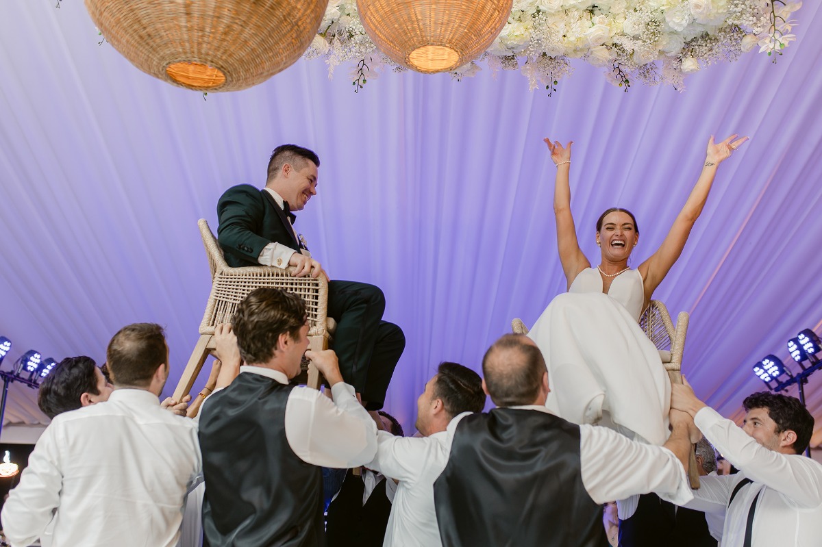 Bride and groom being raised in chairs during reception dance