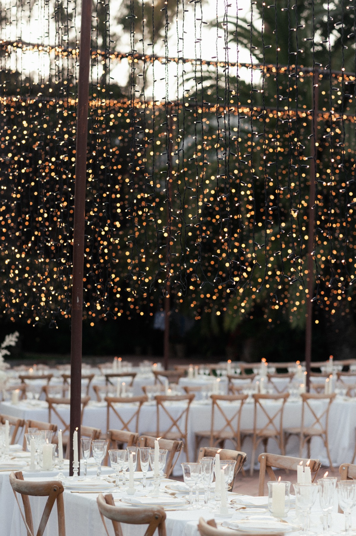 Reception tables with gold-rimmed glasses and string lights