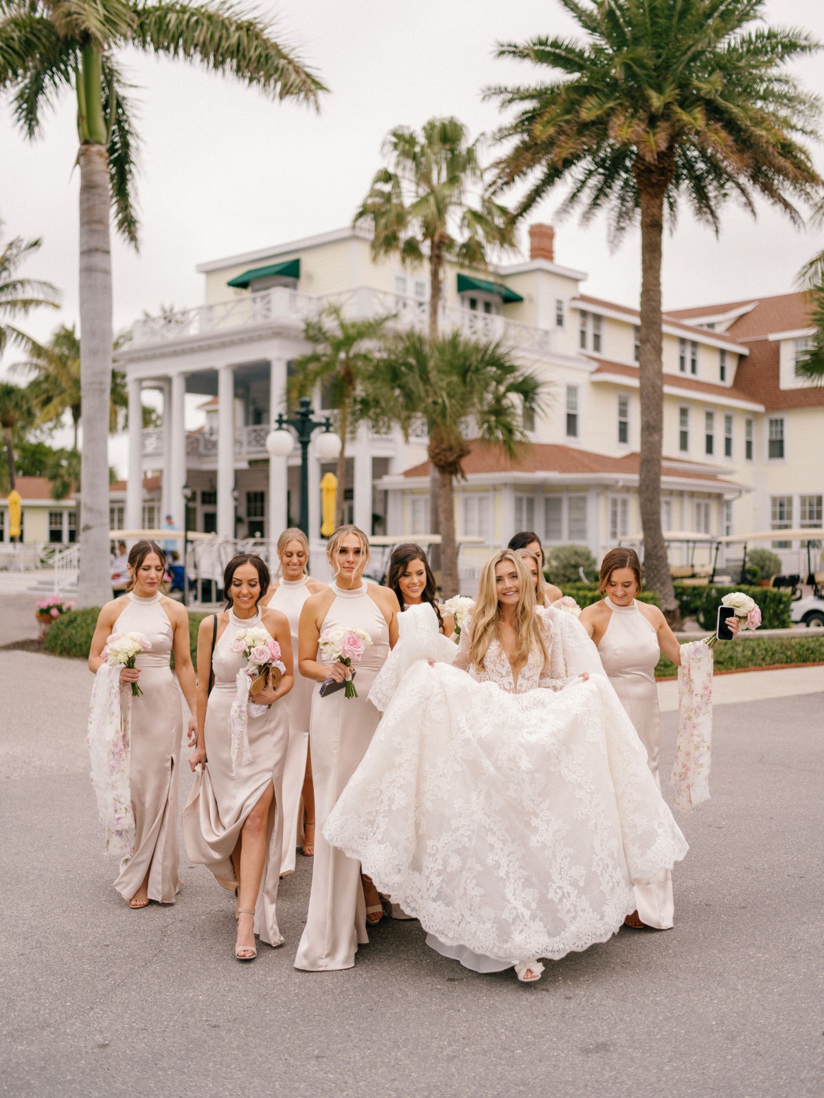 Bride walking with bridesmaids holding her dress up