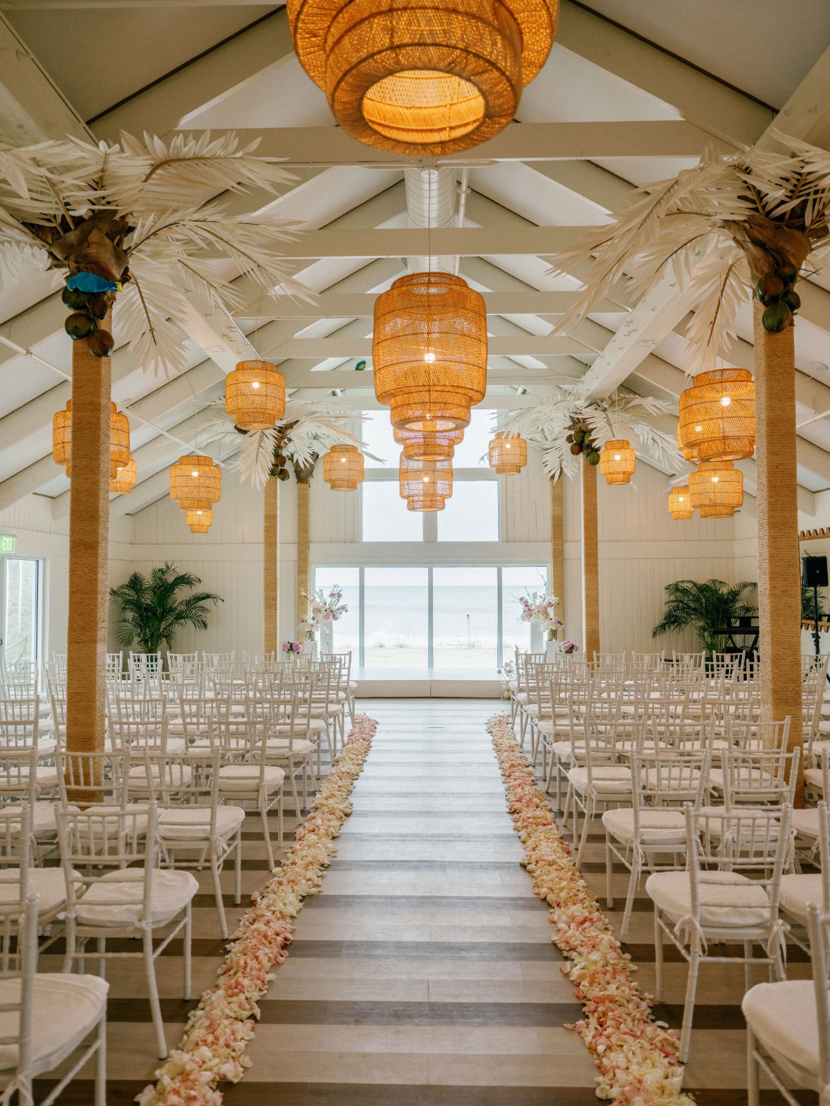 Ceremony room with rattan light fixtures and rose petals lining the aisle